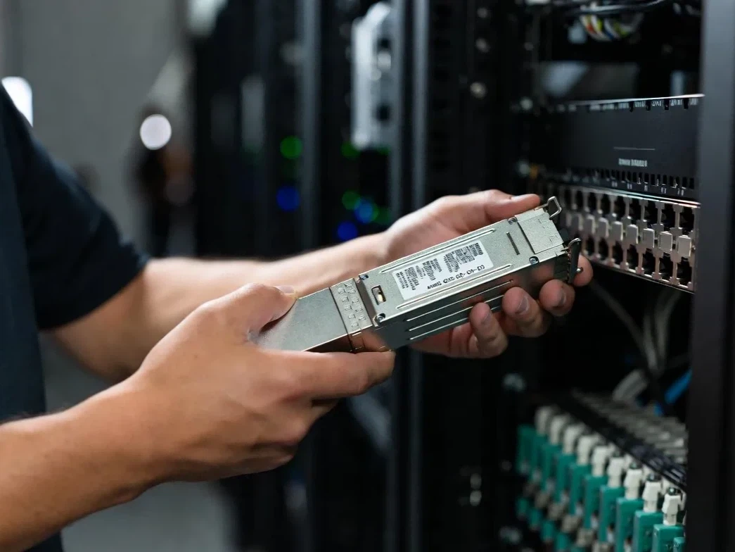 Network technician performing on-site maintenance on a 400G QSFP-DD pluggable transceiver for quick data center link restoration Network technician performing on-site maintenance on a 400G QSFP-DD pluggable transceiver for quick data center link restoration